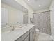 Well-lit bathroom showcasing double sinks with modern fixtures, and a stylish shower curtain at 404 Saddlebred Ln, Locust, NC 28097