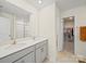 Bathroom with a dual sink vanity, white countertops, and a large mirror, leading to a walk-in closet at 404 Saddlebred Ln, Locust, NC 28097
