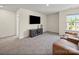 Bright bonus room with carpet, media center, and brown leather sofa, perfect for entertainment and relaxation at 404 Saddlebred Ln, Locust, NC 28097
