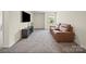 Spacious bonus room featuring a plush carpet, media center, and comfortable brown leather sofa at 404 Saddlebred Ln, Locust, NC 28097