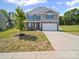 Charming two-story home boasts stone accents, gray siding, well-manicured lawn, and a two car garage at 404 Saddlebred Ln, Locust, NC 28097