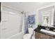 Bathroom with a shower-tub combo, blue patterned shower curtain, and modern sink with dark wood cabinets at 6401 Morehead Rd, Harrisburg, NC 28075