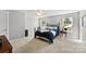 Light-filled bedroom featuring a wrought iron bed, hardwood side table, and a view of trees at 6401 Morehead Rd, Harrisburg, NC 28075