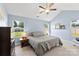 Bright bedroom with neutral tones, a ceiling fan, and two windows overlooking a well-maintained yard at 6401 Morehead Rd, Harrisburg, NC 28075