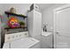 Well-organized laundry area with a washer, dryer, storage cabinet, and shelving for supplies at 6401 Morehead Rd, Harrisburg, NC 28075