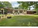 Large backyard featuring a brick patio, fire pit, and mature trees at 7107 Cedarfield Rd, Charlotte, NC 28227