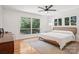 Bright bedroom featuring hardwood floors, ceiling fan, and large windows overlooking mature trees at 7107 Cedarfield Rd, Charlotte, NC 28227
