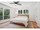 Bright bedroom featuring hardwood floors, ceiling fan, and large windows overlooking mature trees at 7107 Cedarfield Rd, Charlotte, NC 28227