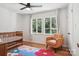 Bright bedroom with hardwood floors, ceiling fan, and a single accent chair facing the three-window view at 7107 Cedarfield Rd, Charlotte, NC 28227