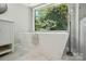 Elegant bathroom featuring a freestanding tub with modern fixtures and a large picture window at 7109 Forney Hill Rd, Denver, NC 28037