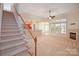 Open-concept living room with a fireplace, a ceiling fan, carpet flooring, and staircase at 8712 Soaring Eagle Ln, Waxhaw, NC 28173