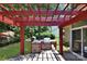 Outdoor kitchen with stone surround, grill, and red pergola on a brick patio at 8712 Soaring Eagle Ln, Waxhaw, NC 28173