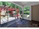 Relaxing sunroom featuring a stone floor and views of the outdoor kitchen with a red pergola at 8712 Soaring Eagle Ln, Waxhaw, NC 28173