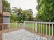 Open-air deck area with a patterned outdoor rug, white railing, and a lush backyard view at 1109 Manchester Ln, Charlotte, NC 28227