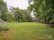 Well-manicured lawn in a spacious backyard, bordered by mature trees and a fence at 1109 Manchester Ln, Charlotte, NC 28227