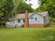 View of the backyard featuring a deck, brick chimney, and mature trees at 1109 Manchester Ln, Charlotte, NC 28227