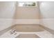 Close up of a neutral-toned bathtub with white subway tile surround and window view at 1109 Manchester Ln, Charlotte, NC 28227