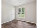 Neutral bedroom with wood-look floors, a window, and a closet with a white door at 1109 Manchester Ln, Charlotte, NC 28227
