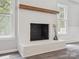 Living room fireplace features painted brick, a rustic wood mantle, and windows at 1109 Manchester Ln, Charlotte, NC 28227