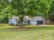 Single-story home with mature trees, lush green lawn, gray siding, and two-car garage at 1109 Manchester Ln, Charlotte, NC 28227