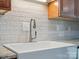 Close-up of kitchen sink with white tile backsplash, granite countertops and a stainless steel faucet at 1109 Manchester Ln, Charlotte, NC 28227