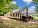 Backyard view showcasing home's deck with grill and patio set amidst lush greenery at 132 General Pemberton St, Stanley, NC 28164