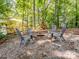 Outdoor fire pit area featuring gravel, surrounded by four Adirondack chairs, and a wooded backdrop at 132 General Pemberton St, Stanley, NC 28164
