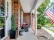 Inviting brick front porch with comfy seating, potted plants, and an American flag waving proudly at 132 General Pemberton St, Stanley, NC 28164