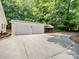 Detached two-car garage featuring a concrete driveway, covered parking area, and surrounded by mature trees at 132 General Pemberton St, Stanley, NC 28164