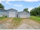 View of the two detached garages with white doors and gravel driveway at 151 Robinson Rd, Gastonia, NC 28056