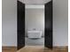Luxurious bathroom featuring a modern soaking tub, herringbone tile floors and elegant fixtures behind black double doors at 1511 Waverly Ave, Charlotte, NC 28203