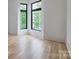 Sunlit bedroom featuring beautiful hardwood floors and black modern corner windows framing lush greenery outside at 1511 Waverly Ave, Charlotte, NC 28203