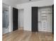 Bright bedroom features light wood floors, walk-in closet with black door, and ensuite bathroom at 1511 Waverly Ave, Charlotte, NC 28203