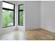Bright bedroom featuring beautiful hardwood floors and modern black windows framing lush greenery outside at 1511 Waverly Ave, Charlotte, NC 28203