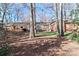 Backyard view featuring a deck, brick accent wall, and mature trees creating a private, wooded ambiance at 251 Gleneagles E Rd, Statesville, NC 28625