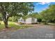A lovely home featuring a side yard and driveway with a canopy of mature trees at 329 W Red Cross Rd, Oakboro, NC 28129