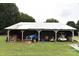 Open-sided shed structure storing a tractor, golf cart, and wood in a grassy, rural setting at 4143 E Maiden Rd, Maiden, NC 28650