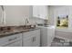 Bright laundry room with granite counters, white shaker cabinets, stainless steel sink, and modern appliances at 4210 Holly Ne Cir, Conover, NC 28613