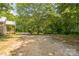 Large backyard area with gravel, trees, and a covered porch, offering ample space for parking and outdoor activities at 4699 Cherrystone Rd, Lancaster, SC 29720