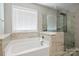 Bright bathroom featuring a tub and glass-enclosed shower with tiled walls at 6907 Hunts Mesa Dr, Fort Mill, SC 29707