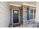 Close-up of the home's stylish front door and stone facade, complemented by black shutters and trim at 6907 Hunts Mesa Dr, Fort Mill, SC 29707