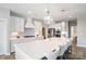 Modern kitchen boasts white cabinetry, stainless steel appliances, and a large island with seating and pendant lights at 6907 Hunts Mesa Dr, Fort Mill, SC 29707