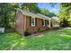 Beautiful brick home with a well-manicured lawn, framed by lush greenery and a covered porch at 9334 New Towne Dr, Matthews, NC 28105
