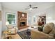 Bright living room with a brick fireplace, hardwood floors, ceiling fan, and an open layout to the kitchen at 9334 New Towne Dr, Matthews, NC 28105