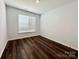 A modern bedroom featuring hardwood floors and a large window, offering ample natural light at 211 Surrey Oak Ln, Charlotte, NC 28216