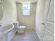 A bright bathroom featuring a pedestal sink, toilet, and a window for natural light at 405 S South St, Gastonia, NC 28052