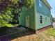 Side exterior featuring green siding, brick foundation, back door, and window accents at 405 S South St, Gastonia, NC 28052