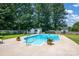 Beautiful in-ground pool surrounded by a concrete patio and lush landscaping, creating a private backyard oasis at 4121 Dover St, Claremont, NC 28610