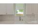 Close up of kitchen sink featuring white cabinets, stainless steel fixtures, and natural light at 5511 Milhaven Ln, Charlotte, NC 28269