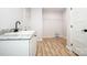 Bright laundry room with a utility sink, storage, and hardwood floors at 7039 Executive Cir, Denver, NC 28037